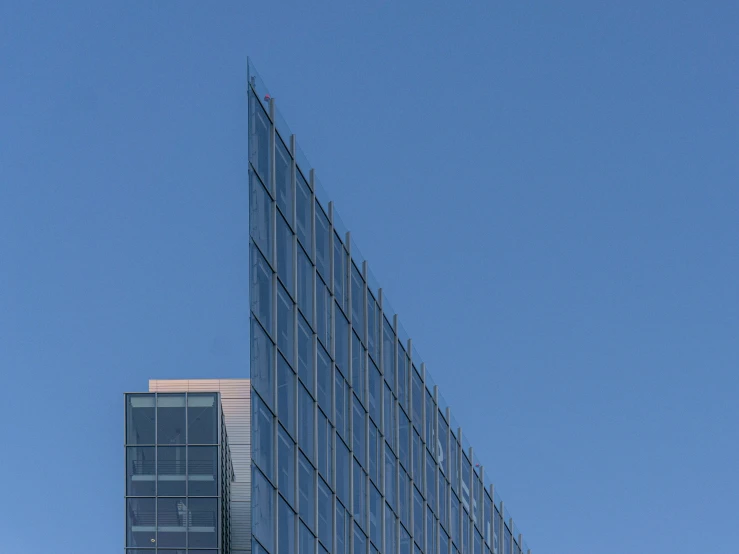 the glass facade of a tall building with a sky background