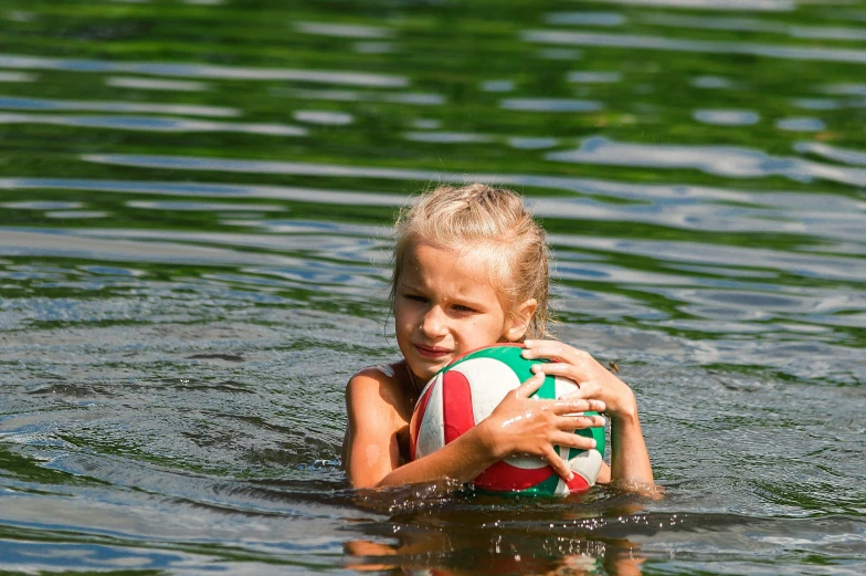 a  holding a beach ball swimming in the water