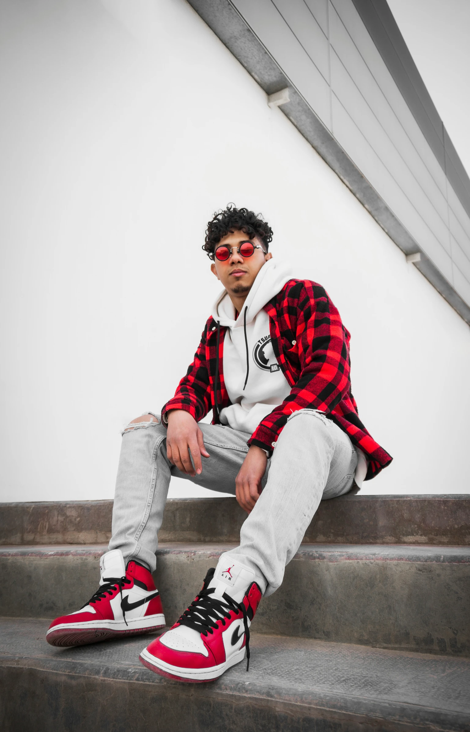 a man sitting down on a set of steps wearing red and white sneakers