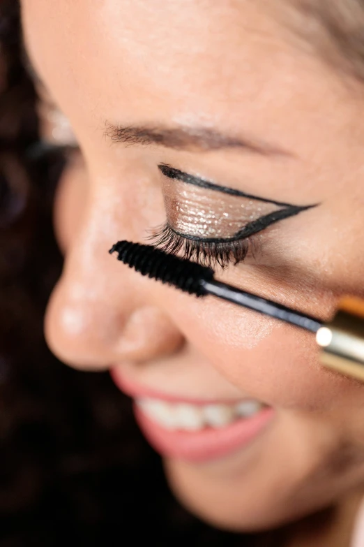 a woman with makeup and mascara brush in her eye