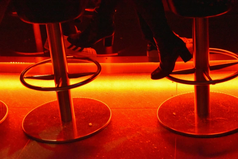 two red stools in front of a neon red light