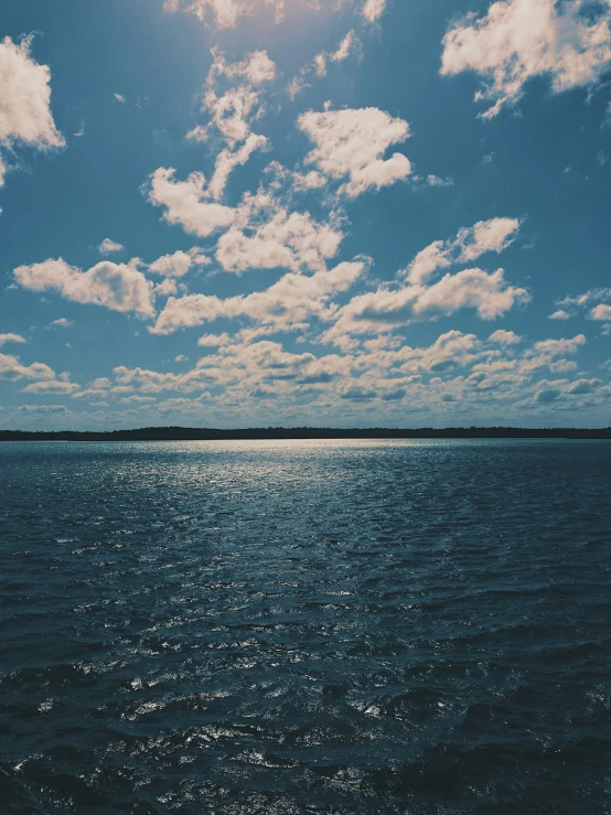 view of blue sky with sun and fluffy white clouds