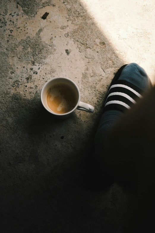 a person sitting on the floor with their legs crossed and holding a mug