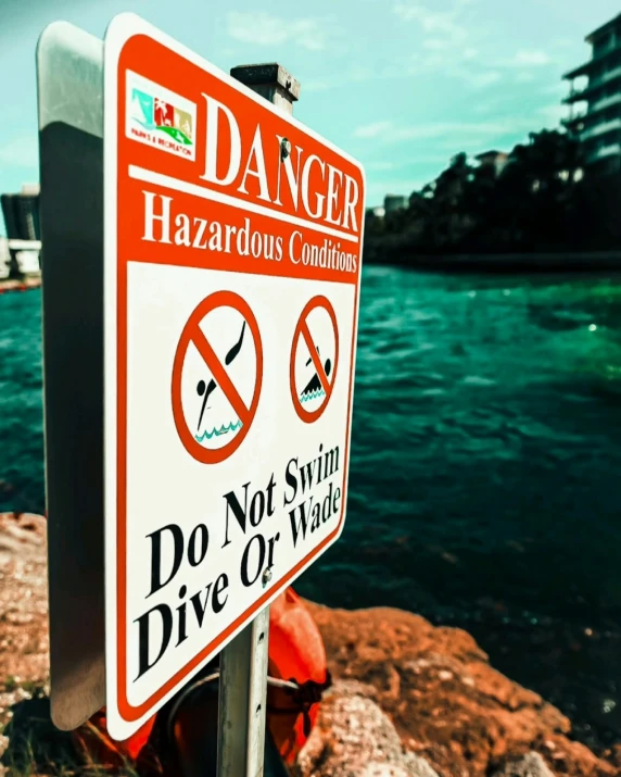 a danger sign posted on the rocks near the water