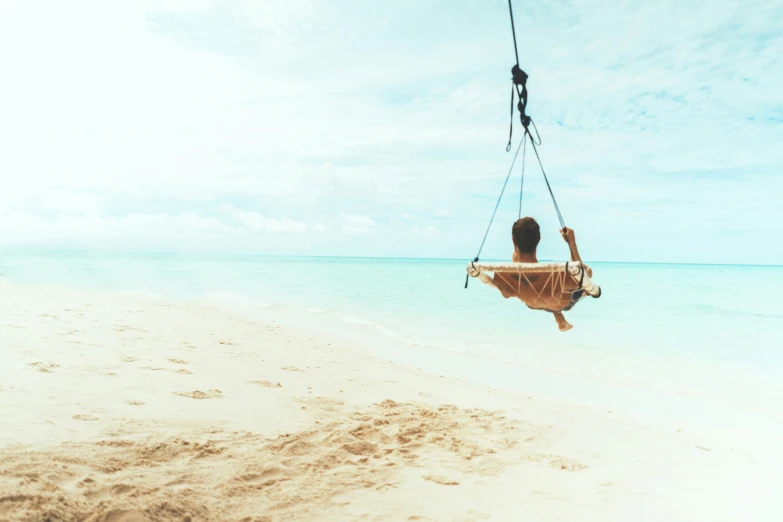 the young woman rides a hammock across the sandy beach