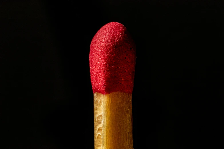 a matchesstick with red tip on it and a wooden handle