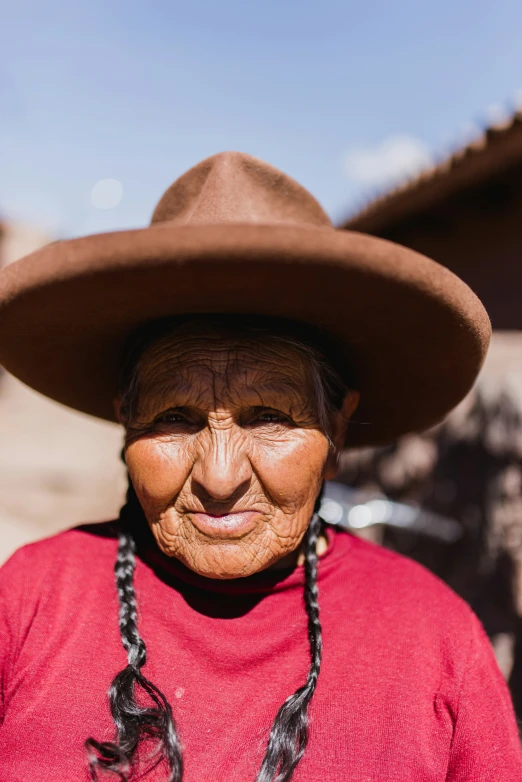 an old woman with a big hat and red top