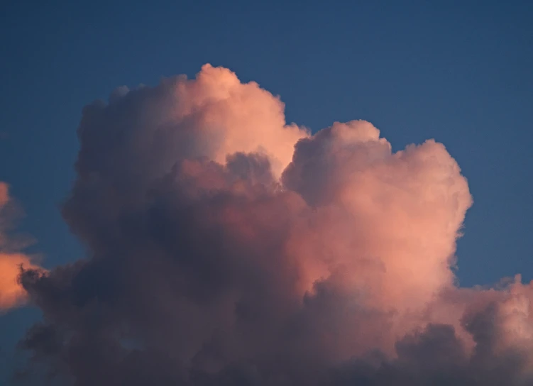 an airplane flies under clouds at dusk