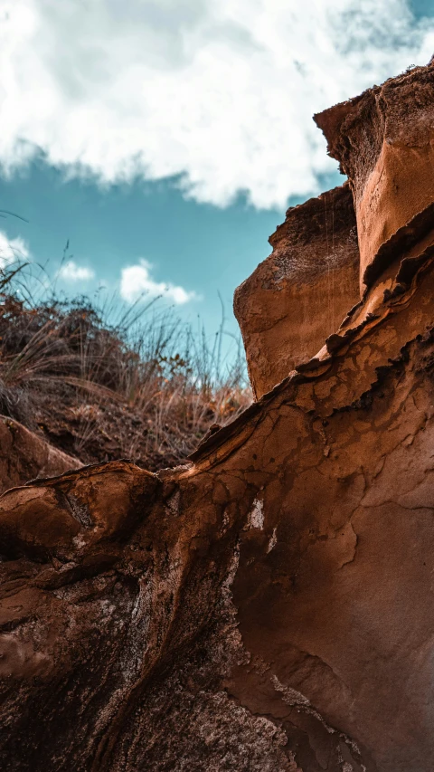 the face of a rock formation with sky in the background