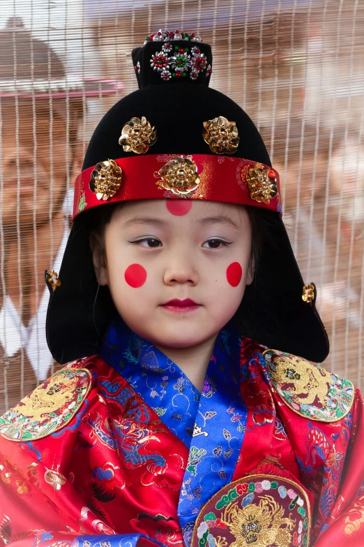 a little girl dressed in oriental attire and hat