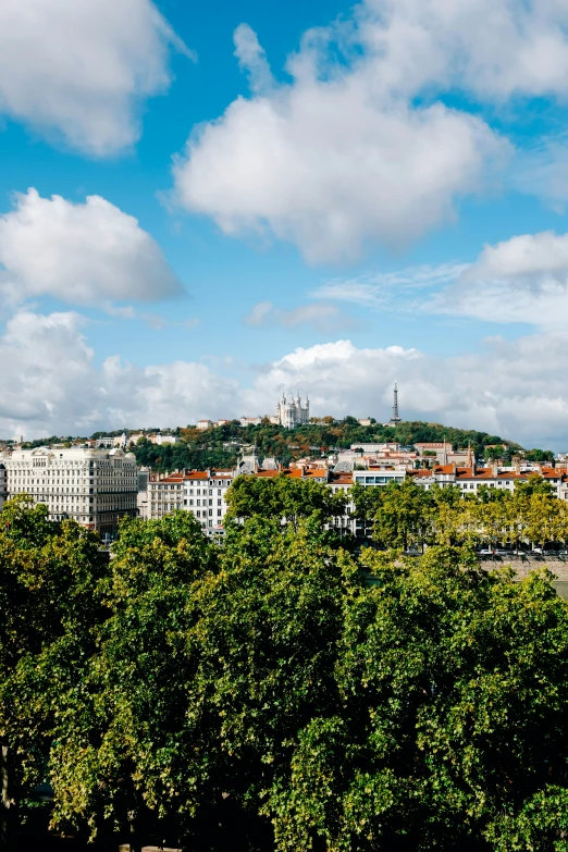 cityscape showing tall buildings on hill, and tall clouds