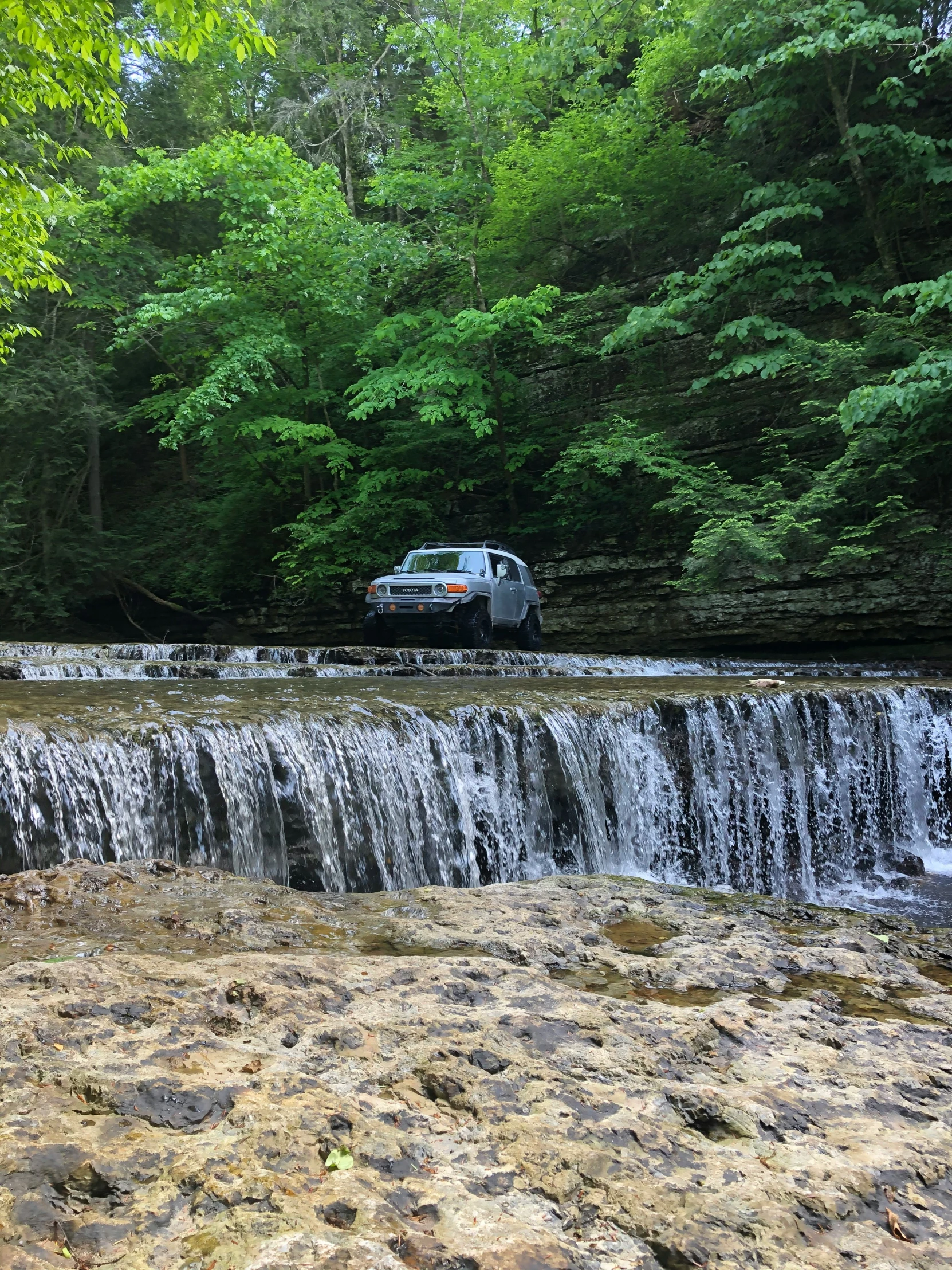 a van is parked near the waterfall of a small river