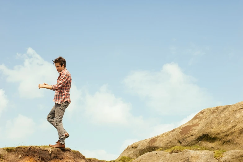 a man holding a frisbee standing on a rock outcropping