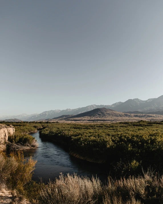 a very wide open field with a stream running through it