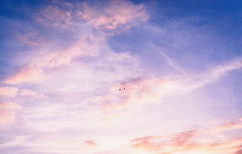 the colorful sky is covered in clouds as a bird flies past