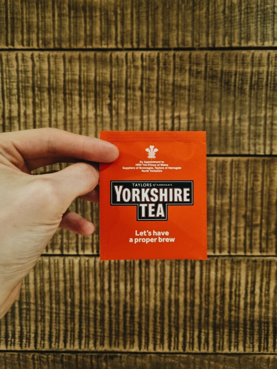 a person holding a orange tea packet in their hand
