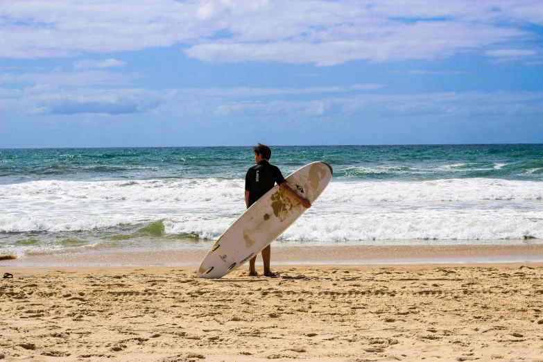 a man on the beach holding a surfboard