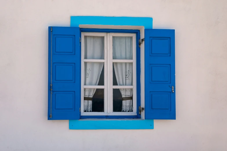 a window with a blue trim, closed and curtains, over white wall and wooden floor