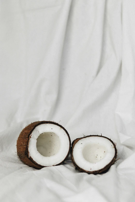 two half - peeled coconuts sitting on top of a white blanket
