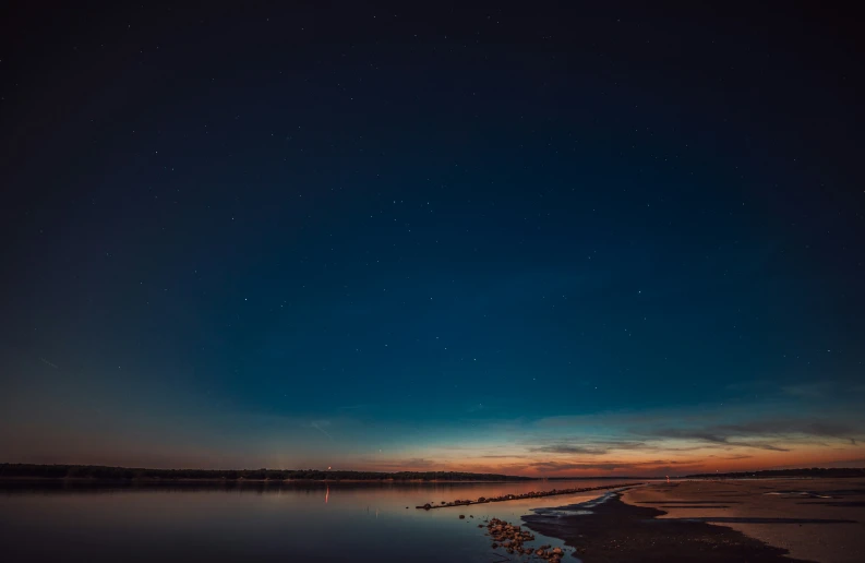 night time sky with stars above the water