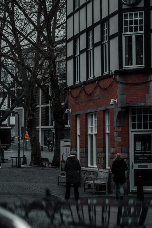 two people are walking down the street by a building