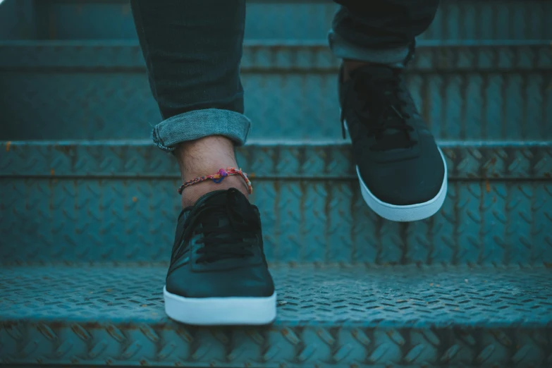 someone wearing black shoes sitting on some steps