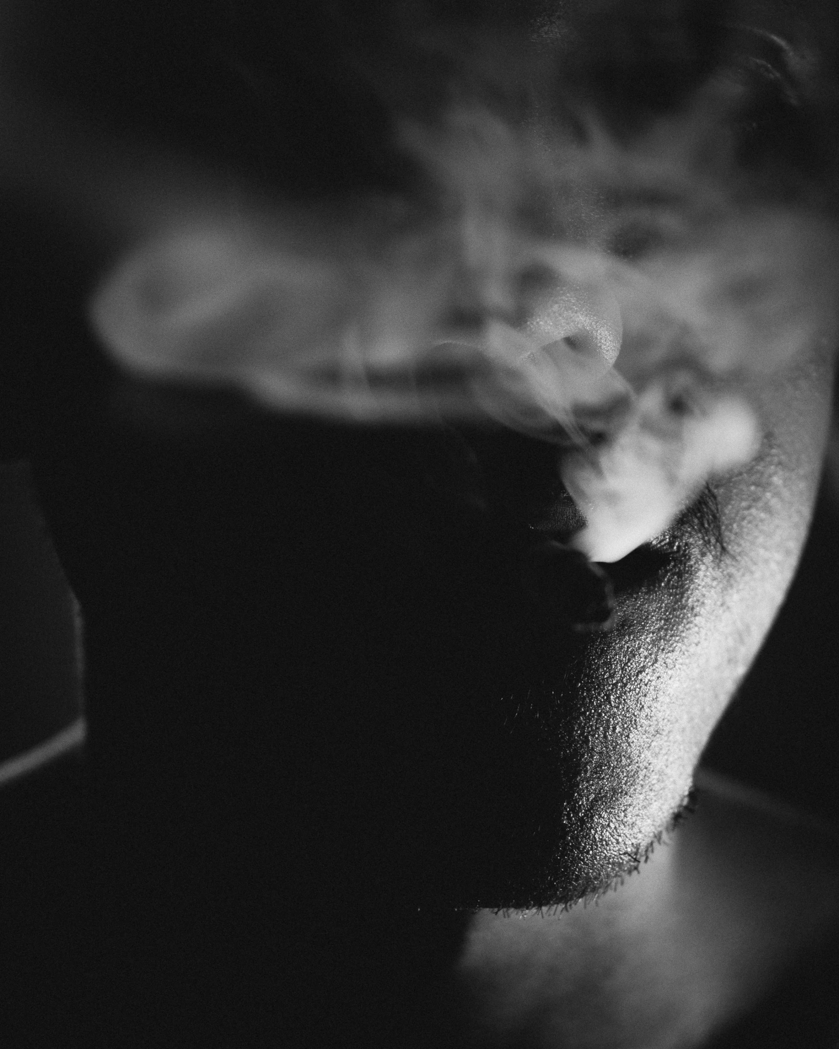 a man smoking cigarette in a dark room