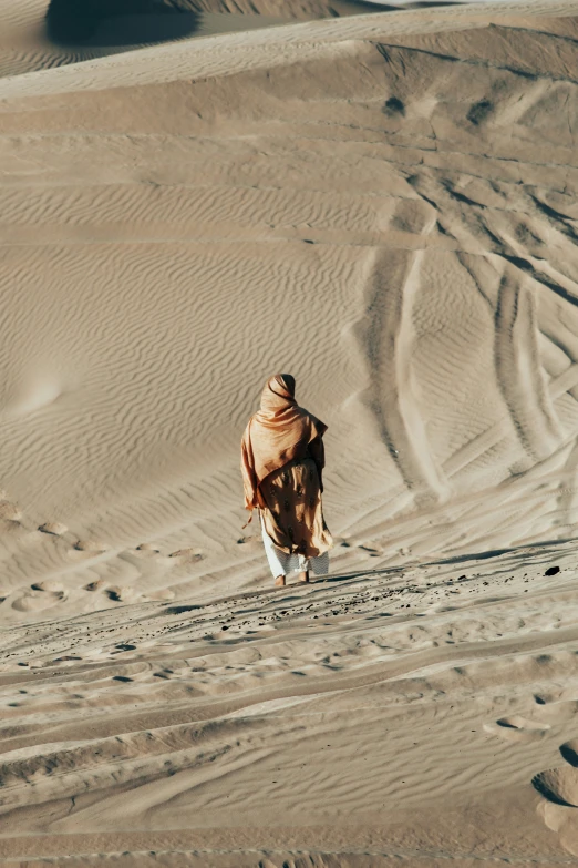 a man walking across a sandy field near some footprints