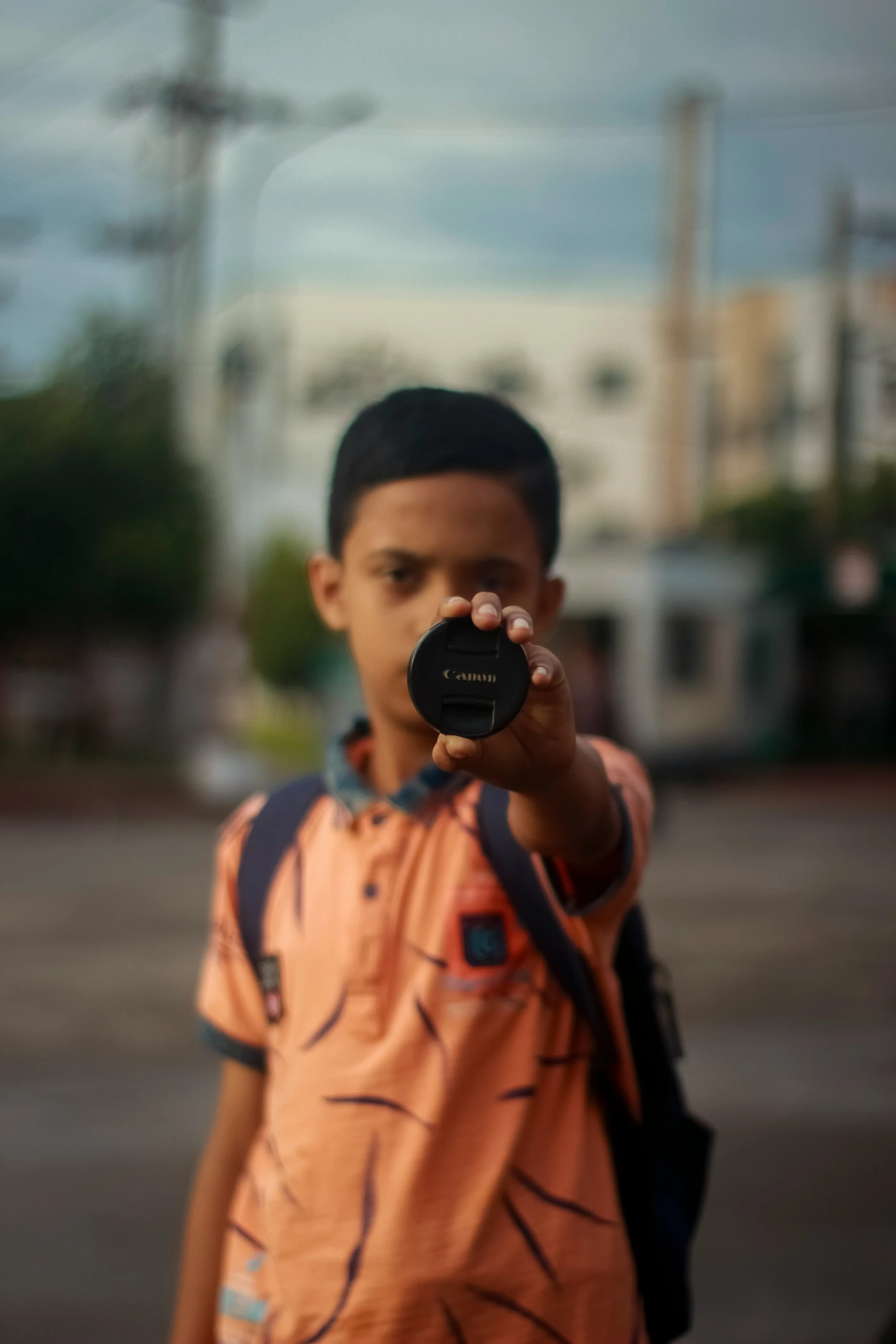 the boy in the orange shirt is holding a black disk