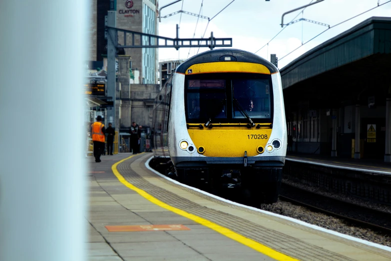 a train at the station with passengers walking by