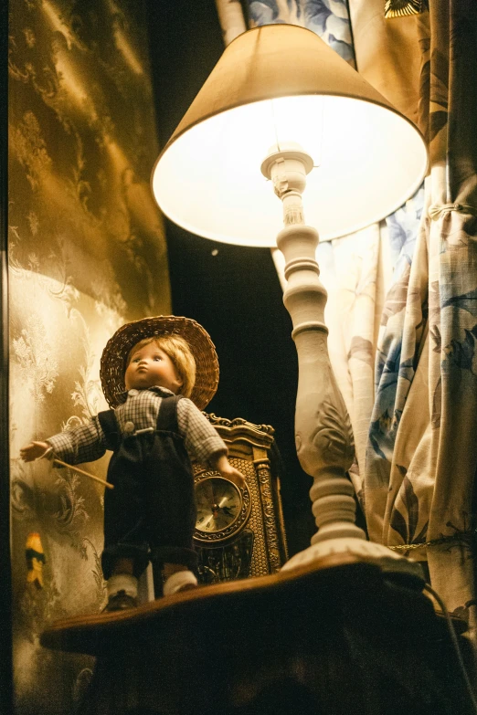 a doll with a hat and coat standing next to a lamp