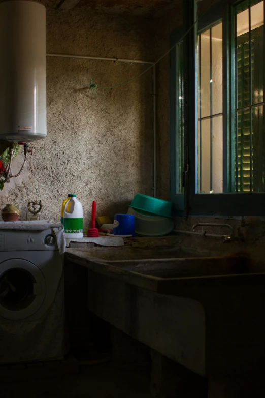 a washer, sink and window in a dirty room