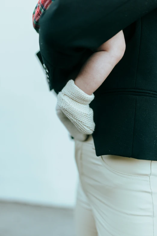 a close - up s of a woman in a black jacket wearing beige pants