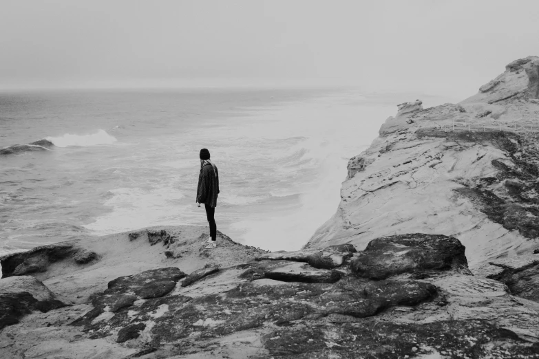 a person looking out at the ocean and some rocks