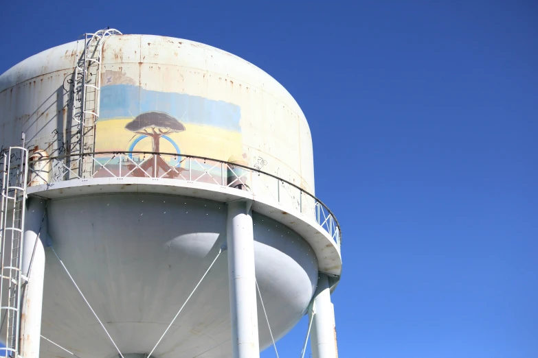 the large, dirty water tower has painted murals on it
