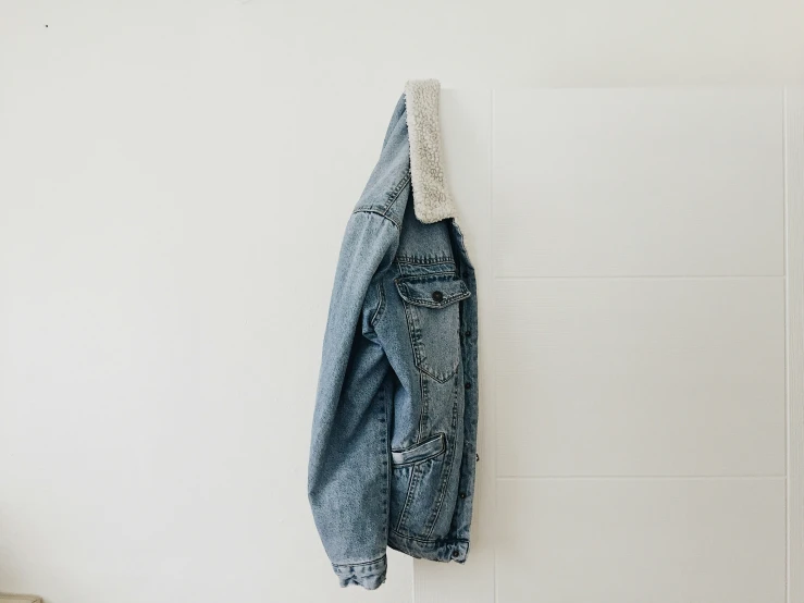 an old denim jacket hangs on a wall