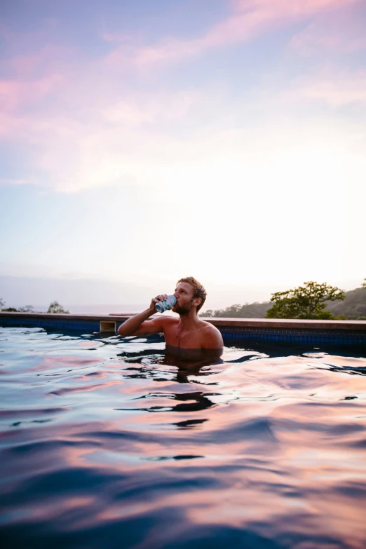 the man is in the pool drinking from his water bottle