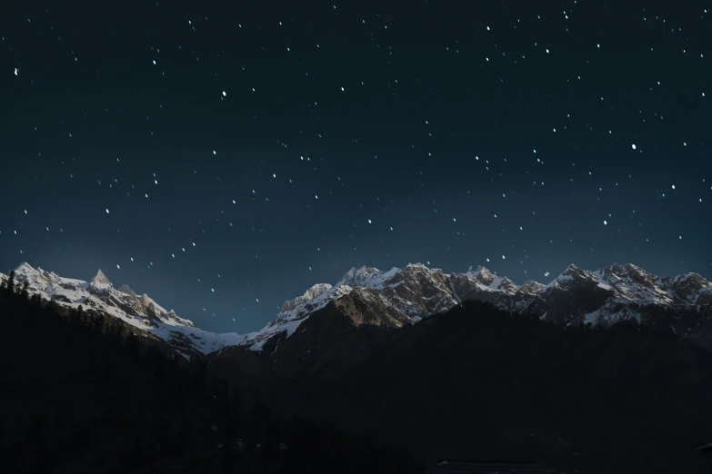 stars are lit on the snowy mountains at night