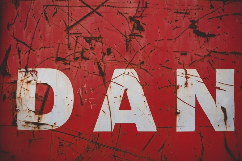 a dirty red painted wall with the word dan written in white