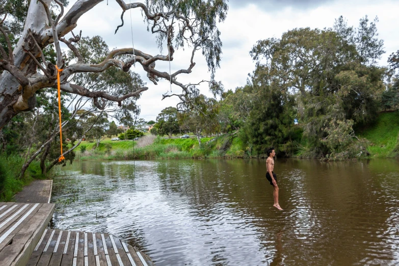 a man wades through shallow water on a boardwalk