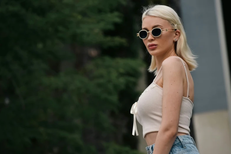 a woman in denim shorts with sunglasses and a white tank top