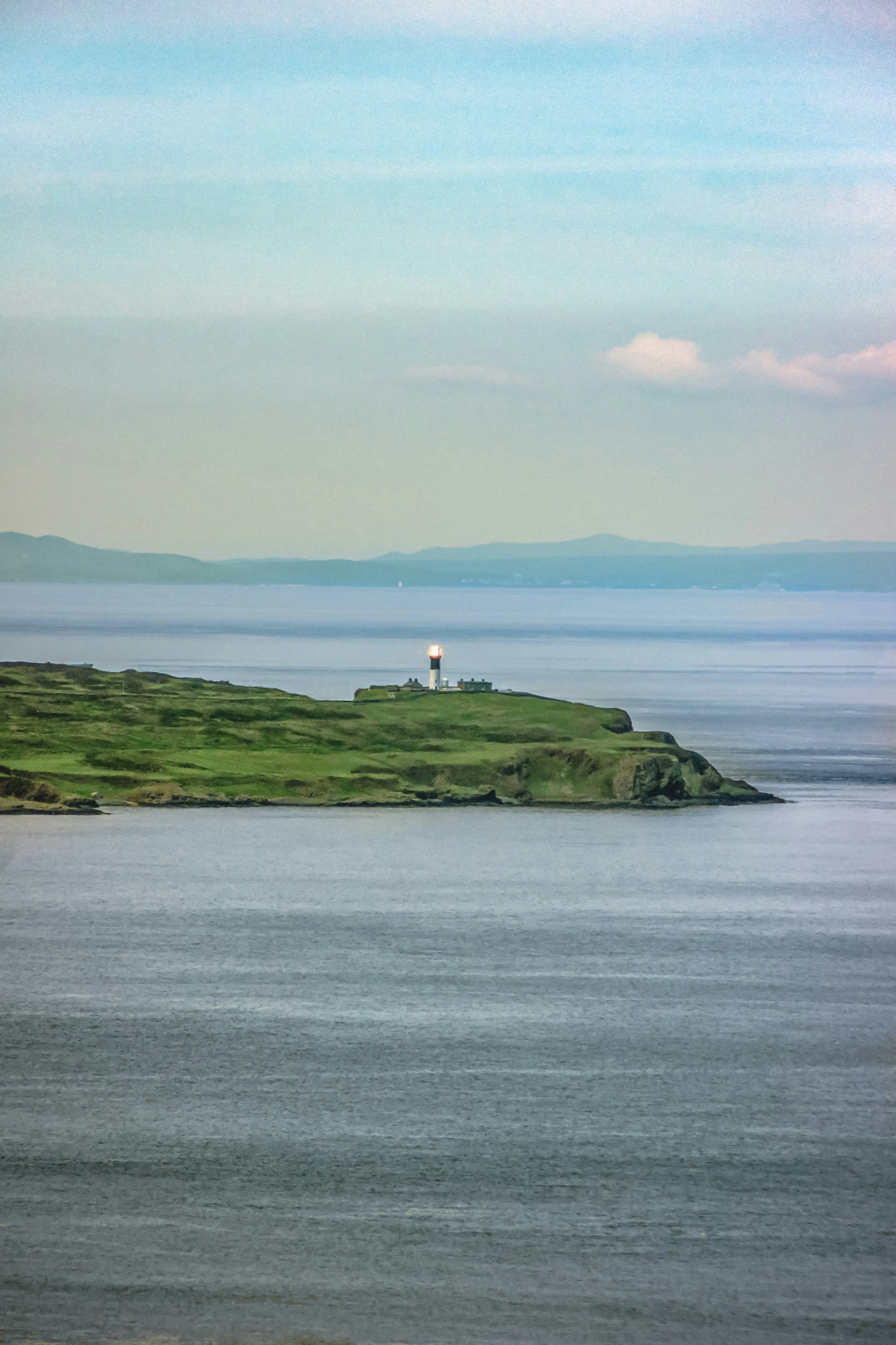 a white light house sitting on top of a green island