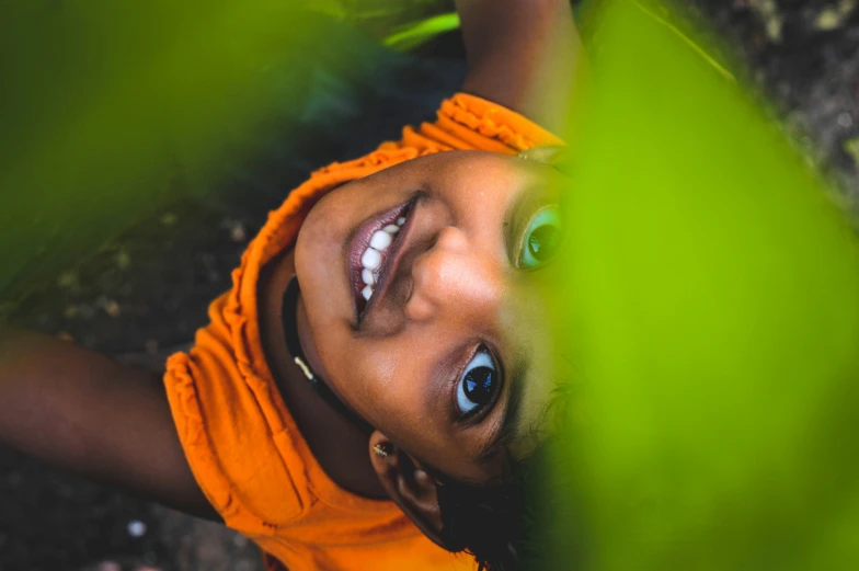 a young child with a bright orange shirt smiling