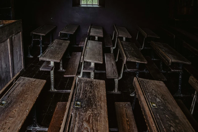 the wooden benches are in the dark with the windows