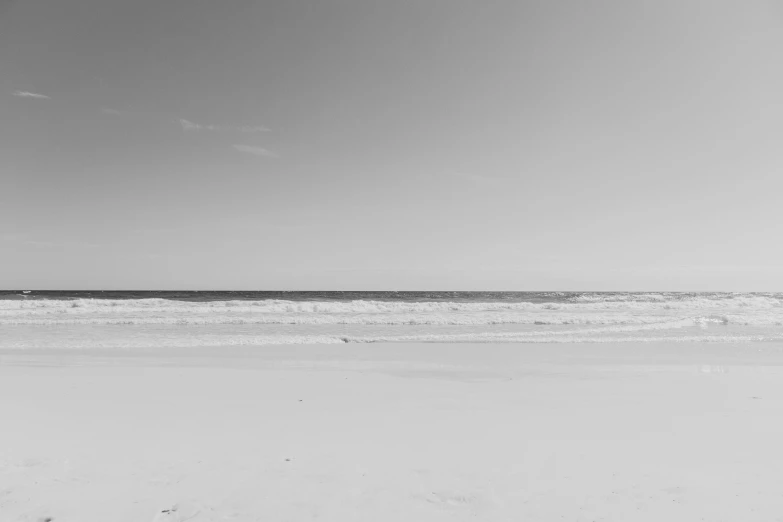 a lone surfer carrying a surfboard into the water