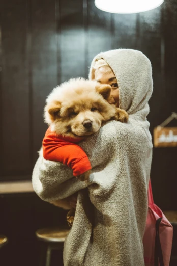 a little dog in a jacket holding onto a woman's back