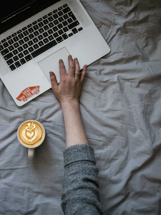 a person laying down on their bed and typing