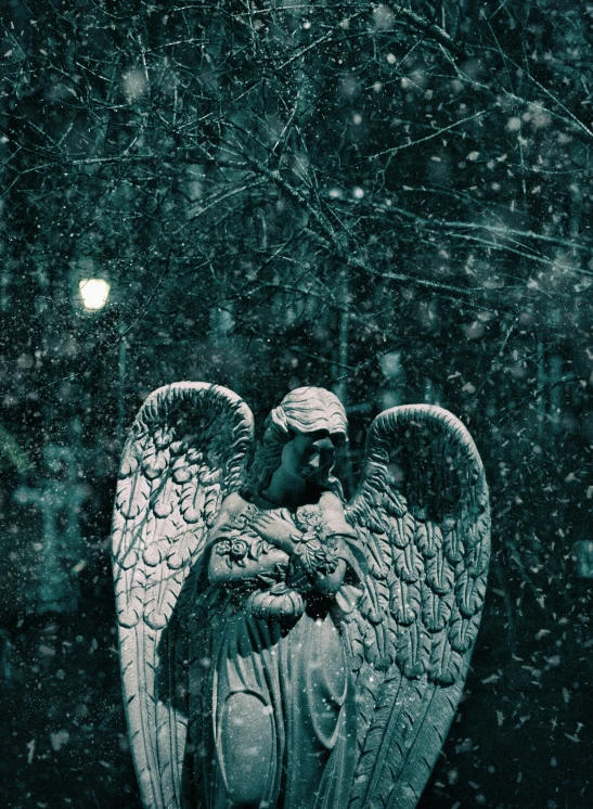angel statue in snow with lantern