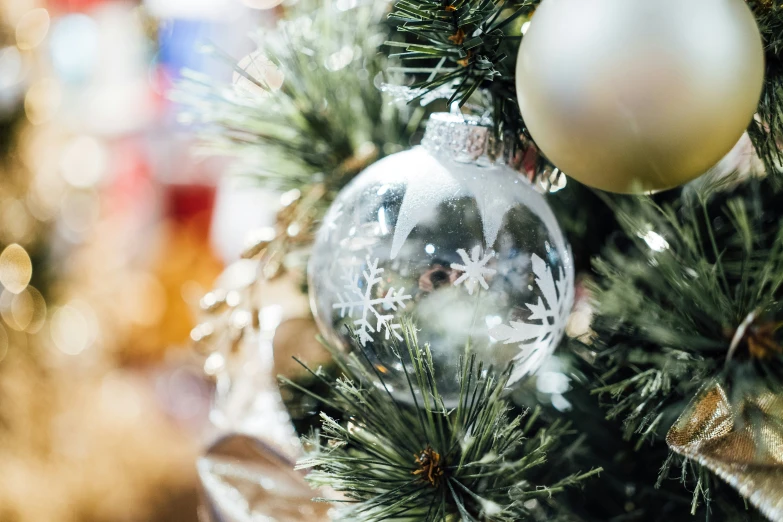 a silver and white christmas ornament sits on a green pine tree