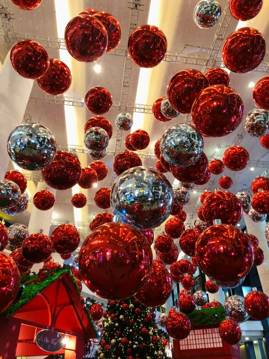 a big christmas tree that has many silver balls hanging from the ceiling